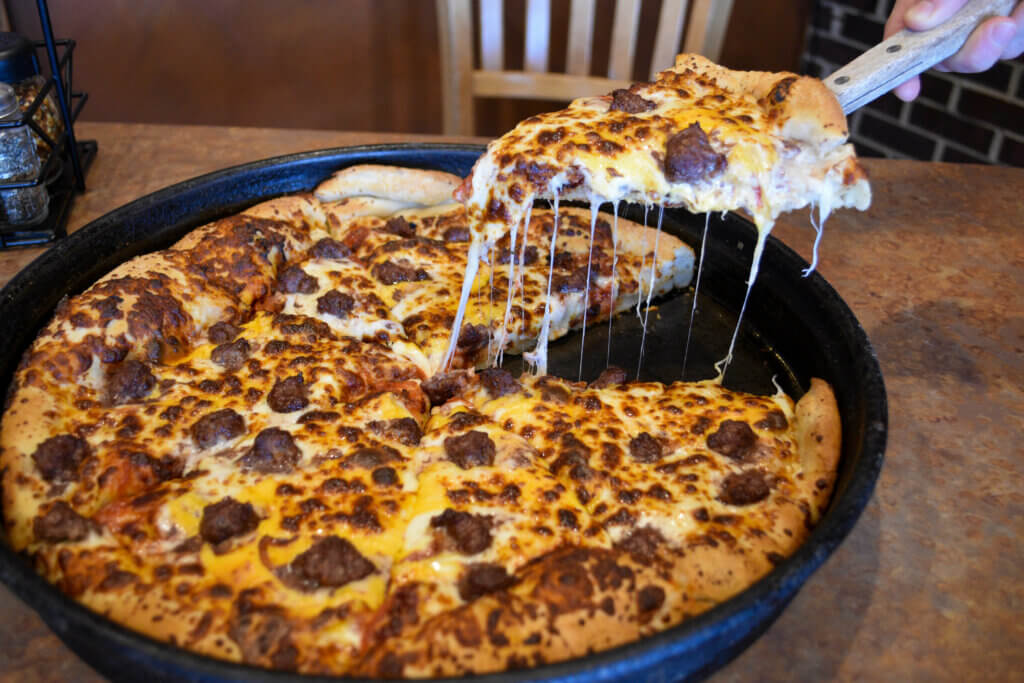 Cutting a piece of Pizza Pub Cheeseburger pizza