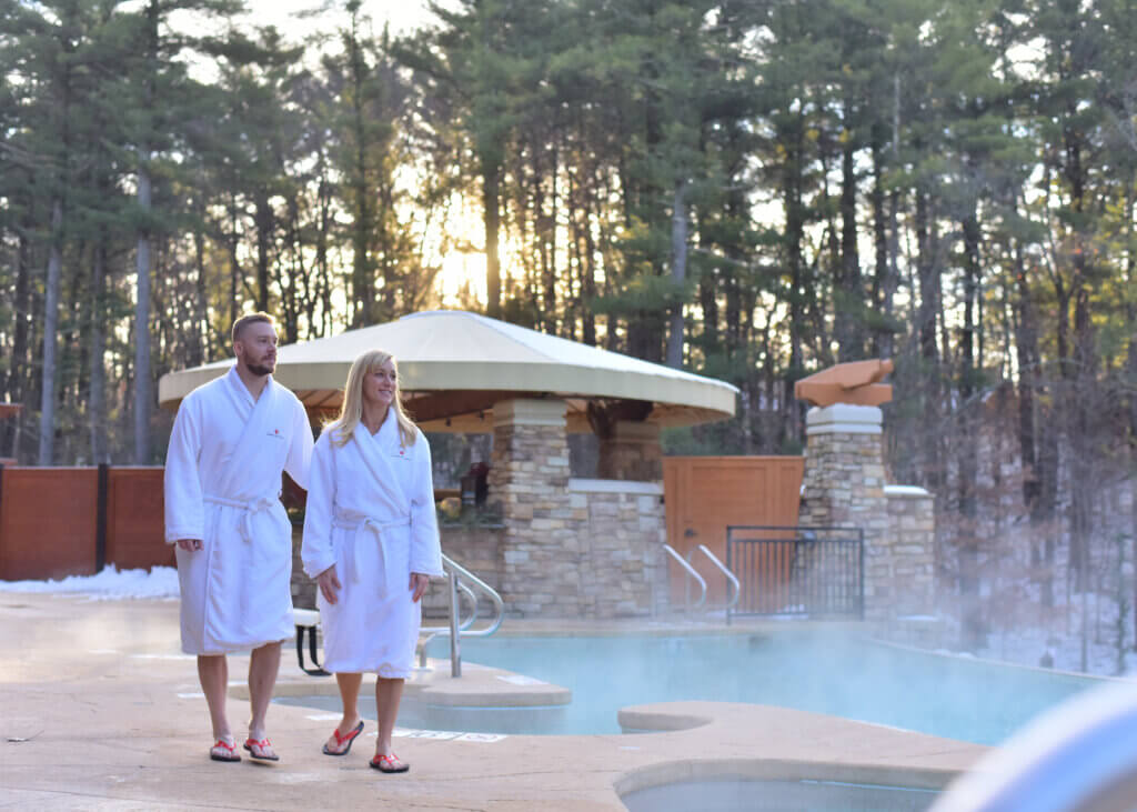 Man and woman walking along outdoor pool at Sundara