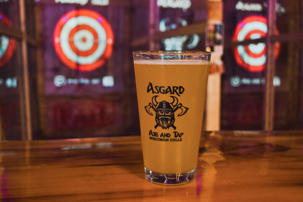 Pint of beer in front of axe throwing lanes