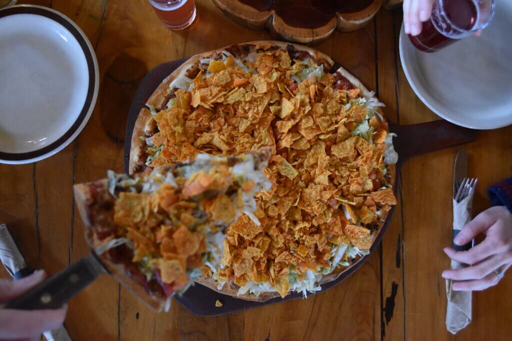 Taco pizza with slice being lifted out