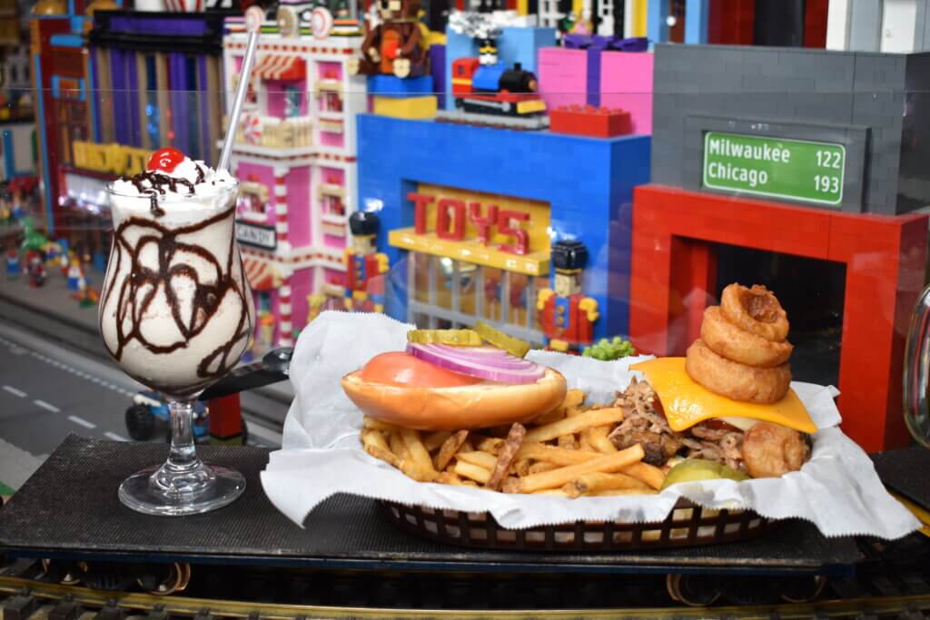 Burger with fries and milkshake riding along the train tracks to the diners' table.