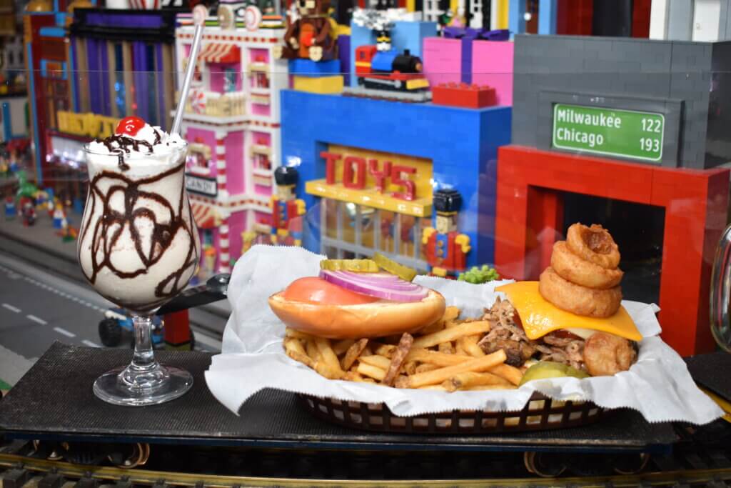 Burger with fries and milkshake riding along the train tracks to the diners' table.