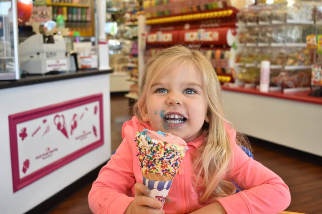 Young girl eating an ice cream cone and laughing at Goody Goody Gumdrop