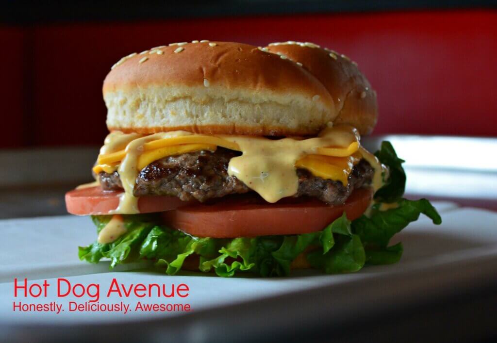 Juicy cheeseburger with lettuce, tomato, and Avenue sauce on a sesame bun